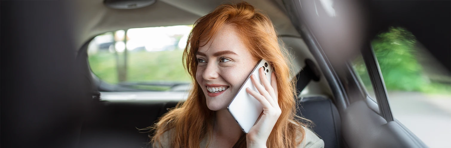 Mulher ruiva falando ao celular dentro de um carro com motorista particular da DS Prime Transporte Executivo